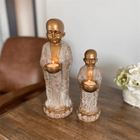 decorative buddhist monk candle holder with candlelight on a console tables