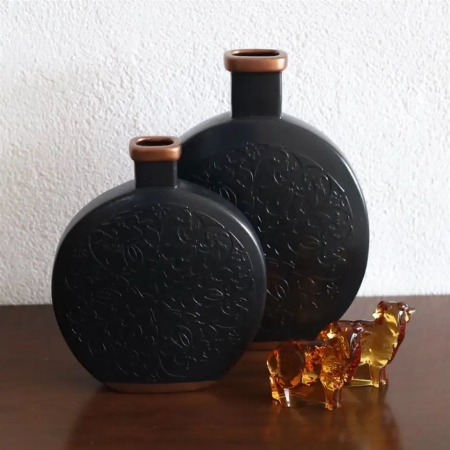 decorative black ceramic vase with copper accents styled on a console table