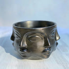 decorative metallic black face planter with succulent plant on shelf