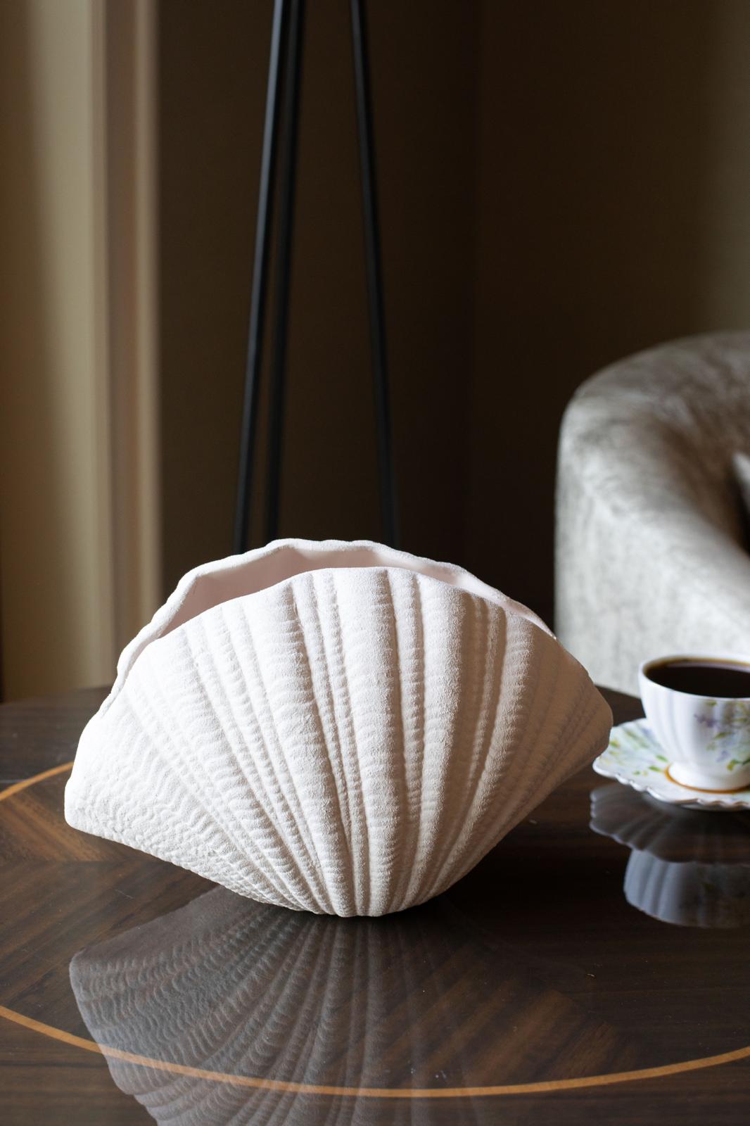 modern oyster shell ceramic vase styled with dried branches on a shelf